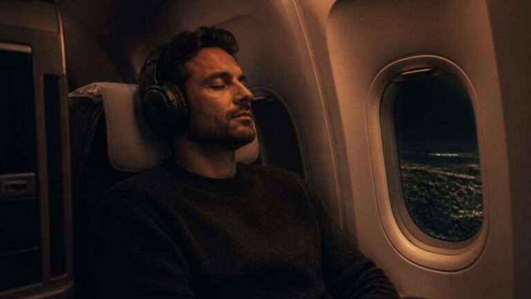 Man wearing noise-canceling headphones in a plane window seat